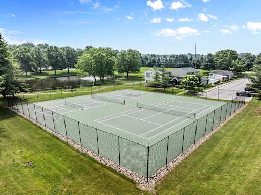 A tennis court surrounded by a fence with a clear blue sky above.