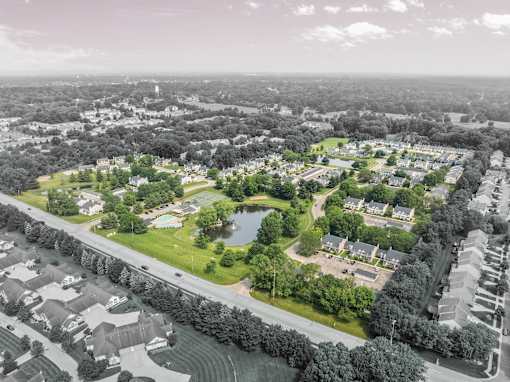 A bird's eye view of a residential area with houses, a swimming pool, and a road.