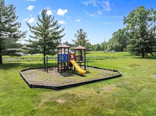 A playground with a yellow slide and a red roof.