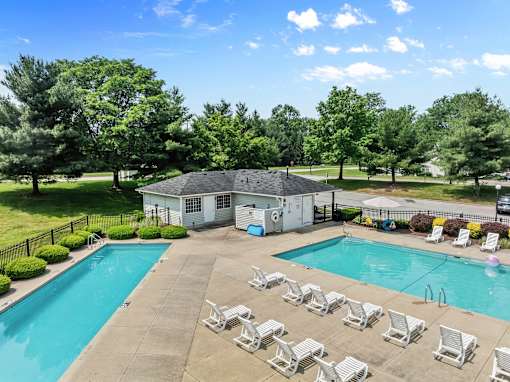 A pool with chairs and a house in the background.