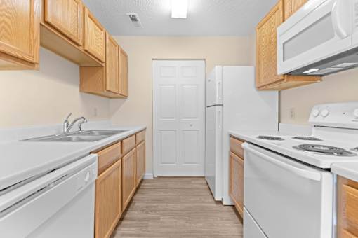 A kitchen with white appliances and wooden cabinets.