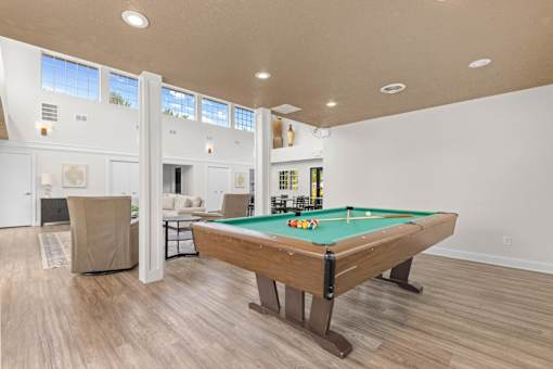 A pool table is in the middle of a room with a light colored floor and walls.