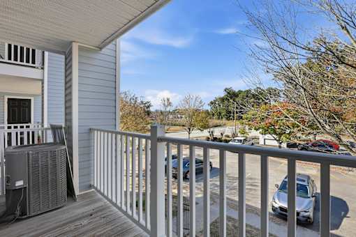 A balcony with a railing and a car parked in the background.