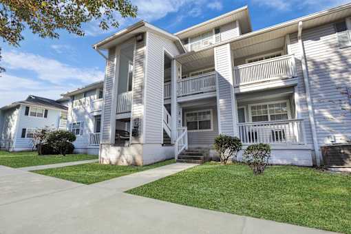 Apartment building with a white facade and a green lawn in front.