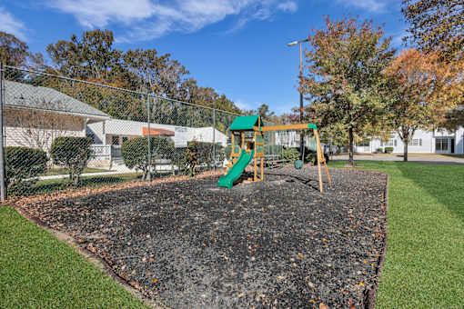 A playground with a green slide and a sandbox.