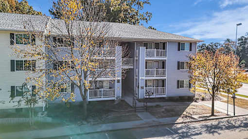 A white apartment building with a tree in front of it.