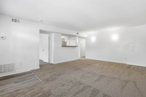 A large, empty room with a carpeted floor and white walls.