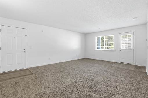 A room with a carpeted floor, a window with blinds, and a door.