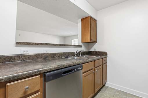A kitchen with a granite countertop and wooden cabinets.