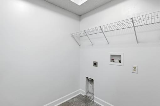 A white room with a metal rack on the ceiling and a small shelf with two objects on it.