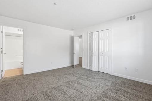 A large, empty room with carpeted flooring and white walls.