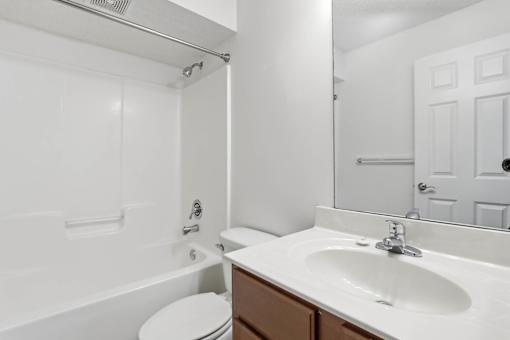 A white bathroom with a toilet, sink, and mirror.