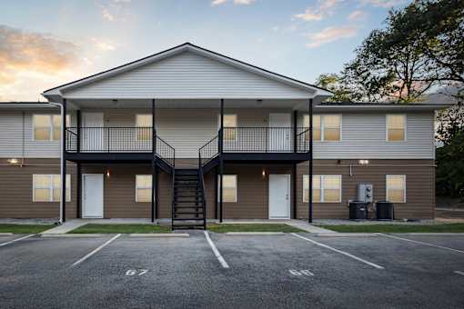A two-story apartment building with a parking lot in front.