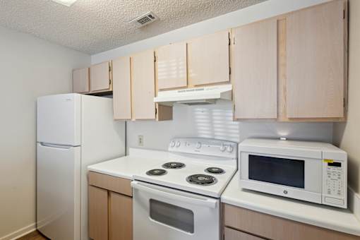 A kitchen with a white refrigerator, white stove, and white microwave.
