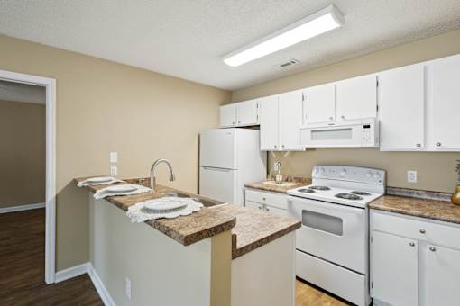A kitchen with white appliances and a granite counter.
