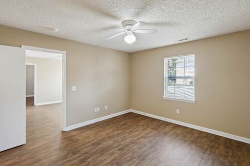 Empty room with a ceiling fan and a window.