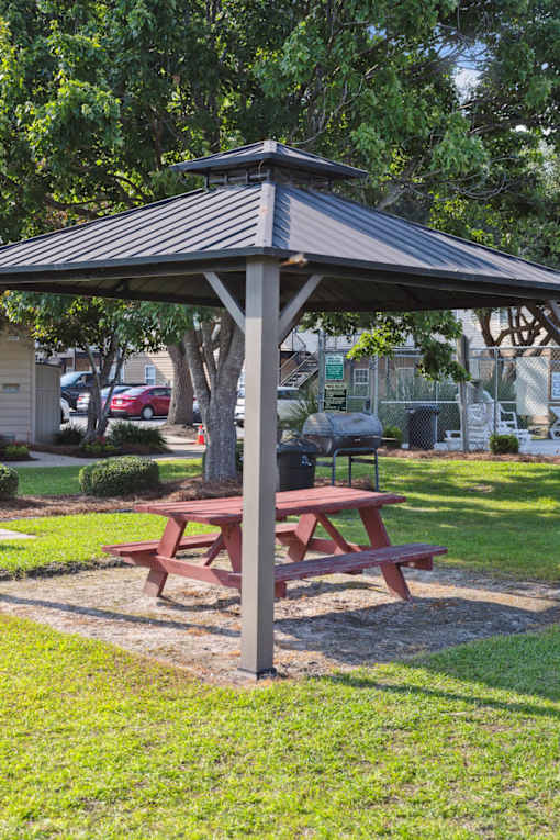A picnic table is under a canopy in a park.