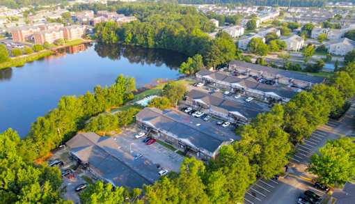 A parking lot is surrounded by trees and a body of water.