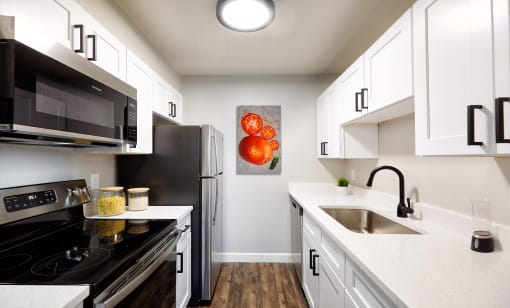 an apartment kitchen with white cabinets and stainless steel appliances