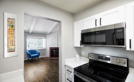 a kitchen with a stove and a microwave and a living room
