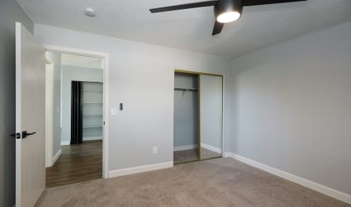 an empty living room with a closet and a ceiling fan