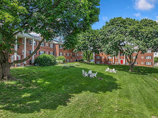 A large grassy area with trees and a row of buildings in the background.