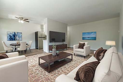 A living room with a white couch and a brown throw pillow.