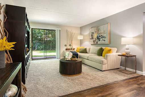 A living room with a white couch and a painting on the wall.