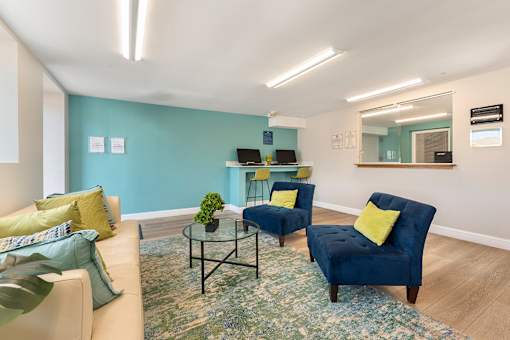 A living room with a blue chair and a glass table.