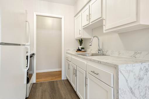 A kitchen with white cabinets and a marble countertop.