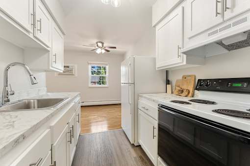 A kitchen with white cabinets and a black stove top oven.