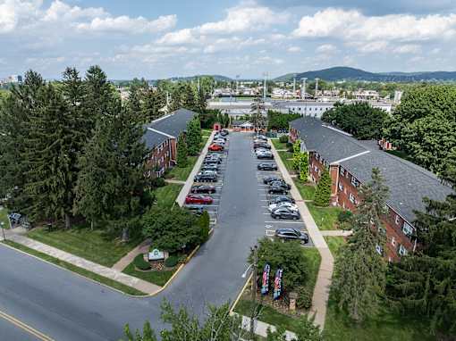 A parking lot is surrounded by trees and a road.