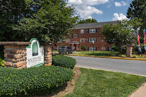 A sign for Society Hill Apartments stands in front of a brick building.