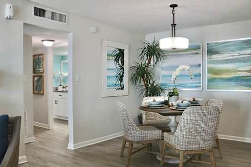 A dining room with a table set for two and a painting on the wall.