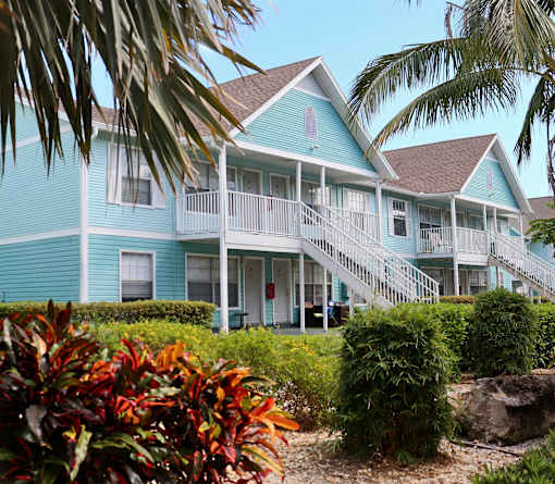 A blue house with a white balcony and stairs leading to the front door.