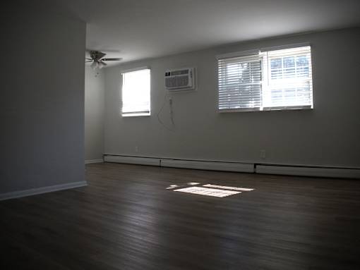 an empty living room with wood floors and a window