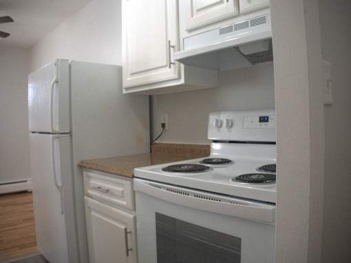 a kitchen with white appliances and white cabinets and a refrigerator