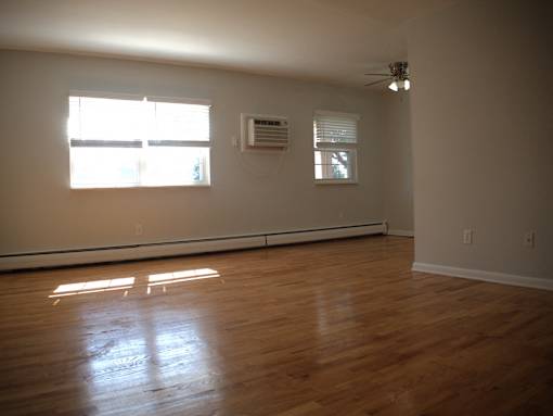 an empty living room with wood floors and a window