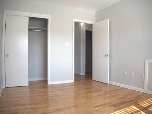 an empty living room with a wood floor and three closet doors