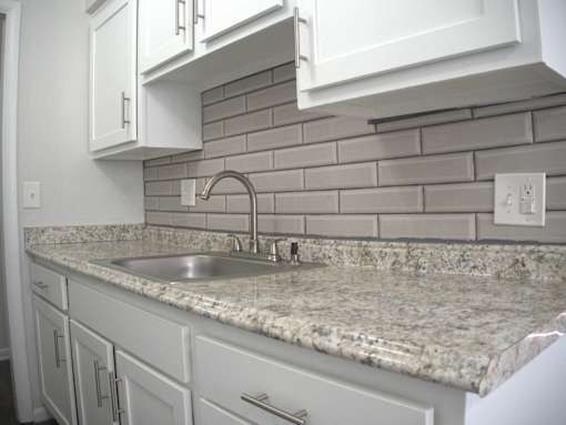 a kitchen with white cabinets and granite counter tops and a sink