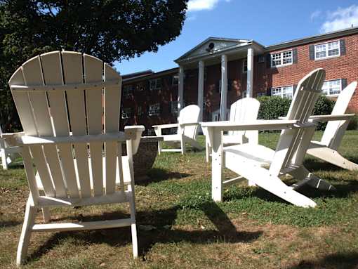 a group of adirondack chairs and a table in front of a building