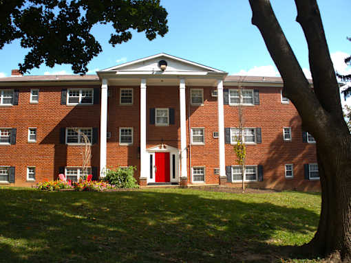 a large brick building with a red door and a tree