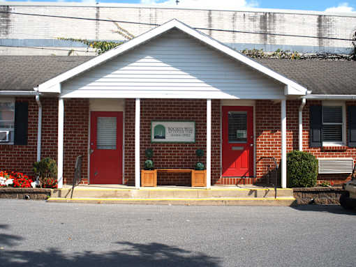 a red brick building with two red doors and a sign on the front
