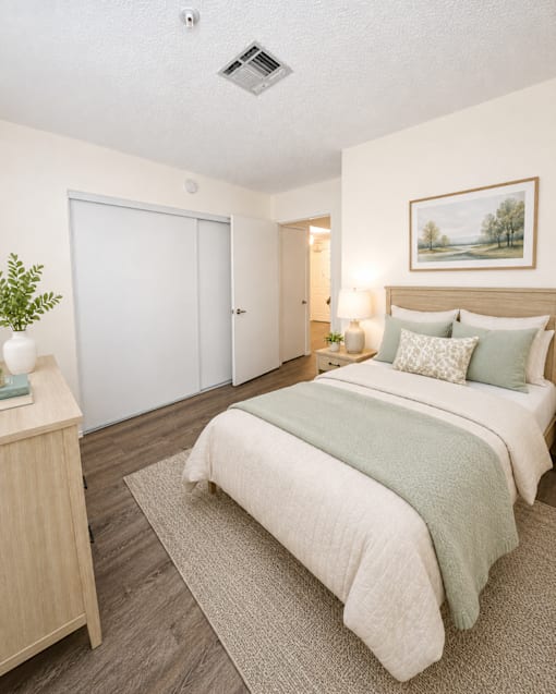 A bedroom with a bed, nightstand, and painting on the wall.
