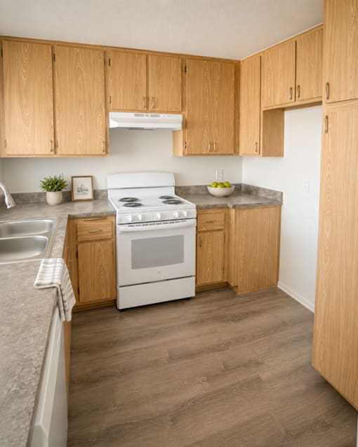 A kitchen with wooden cabinets and a white stove top oven.