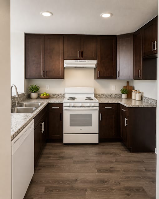 A modern kitchen with a white stove top oven and dark brown cabinets.