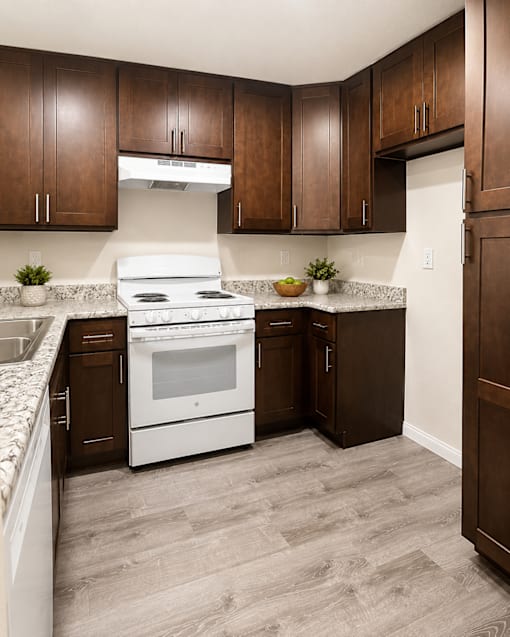 A kitchen with brown cabinets and a white stove top oven.