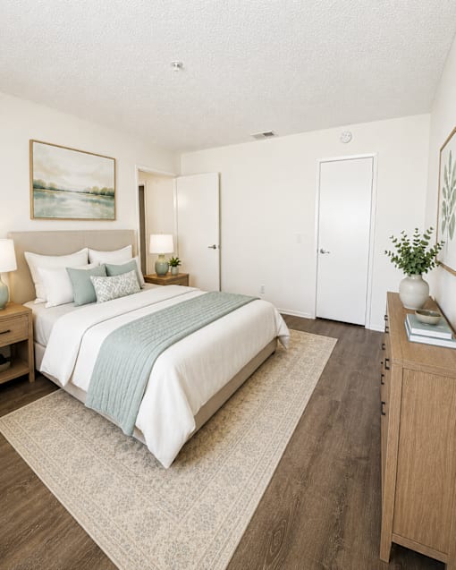 A bedroom with a bed, nightstand, and a painting on the wall.