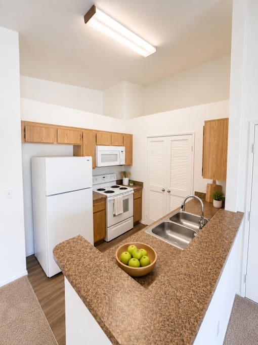 A kitchen with a bowl of green apples on the counter.