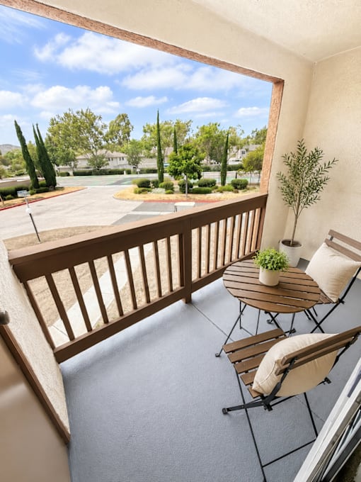 A balcony with a table and chairs overlooking a parking lot.